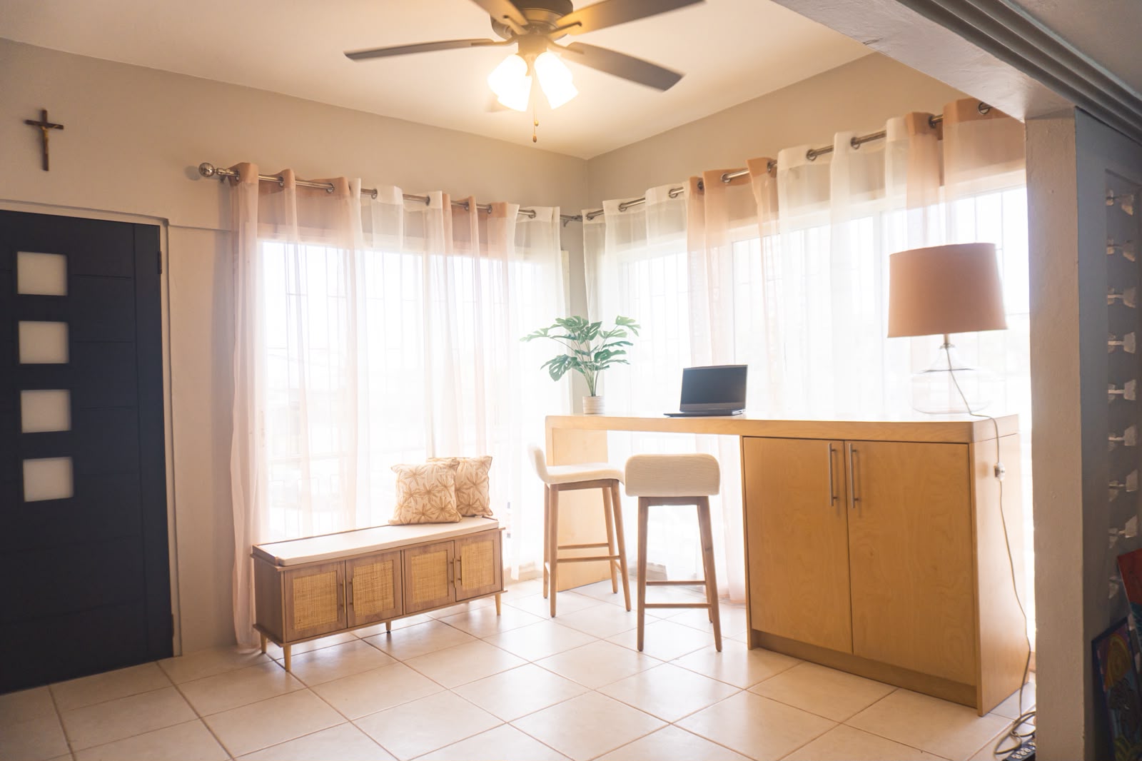 Bright entry with sheer drapes, rattan bench and an oak work counter.