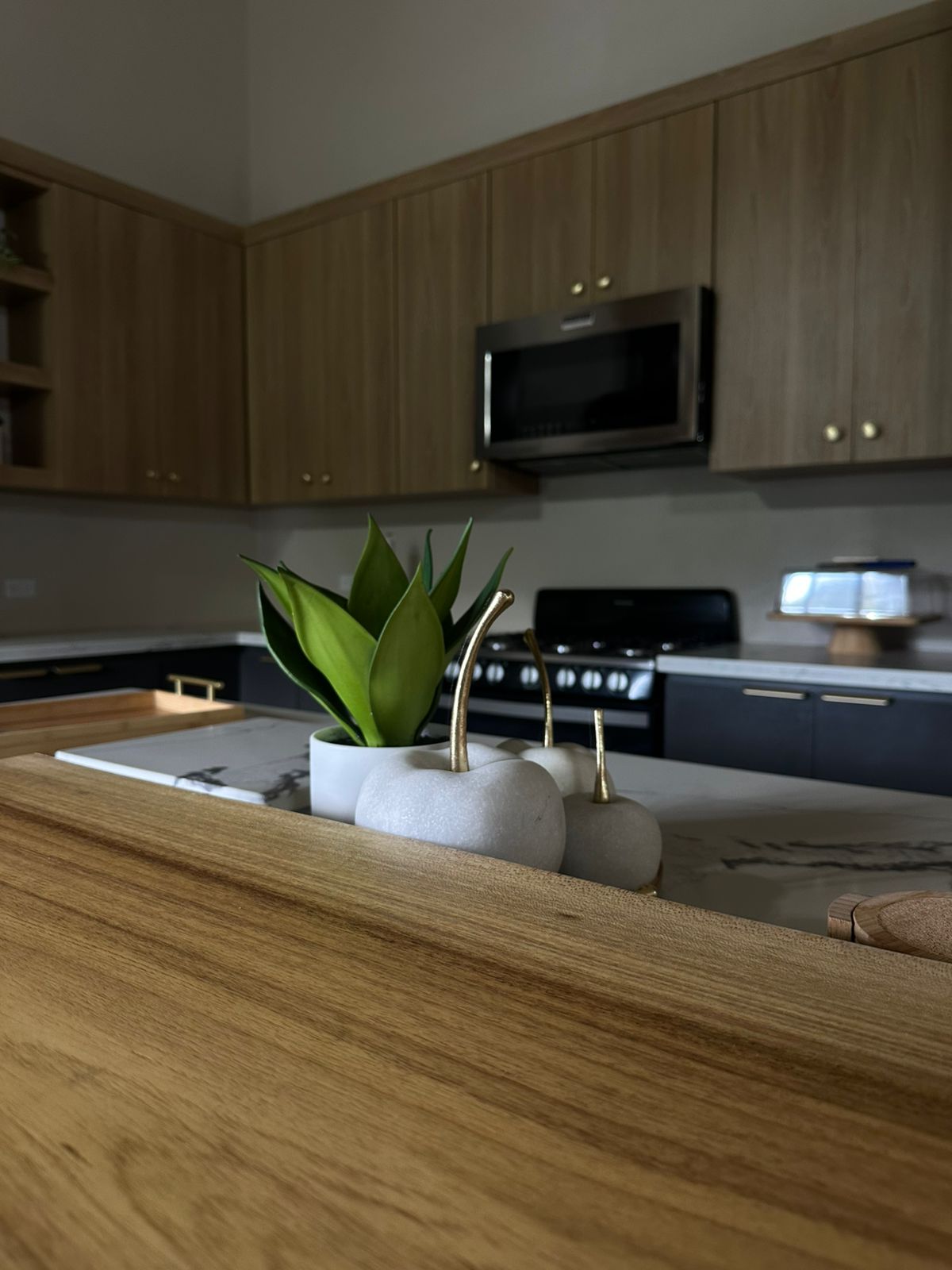Warm wood uppers, navy base cabinets and a styled marble island vignette.